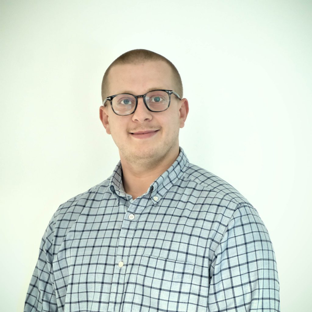 Samuel in a checked shirt smiling at the camera