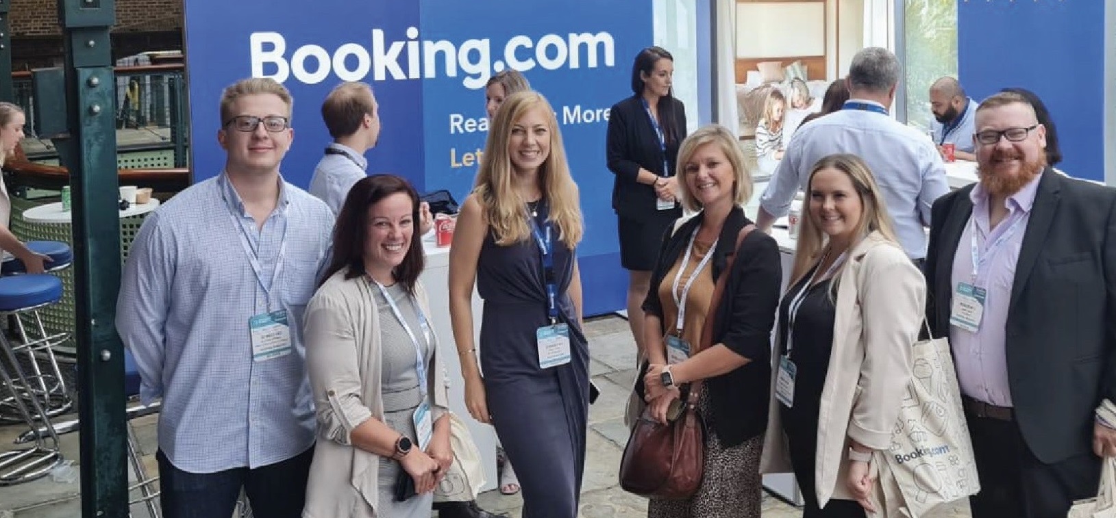 A cheerful group of people smiling and posing together at a Booking.com event, capturing a fun moment.